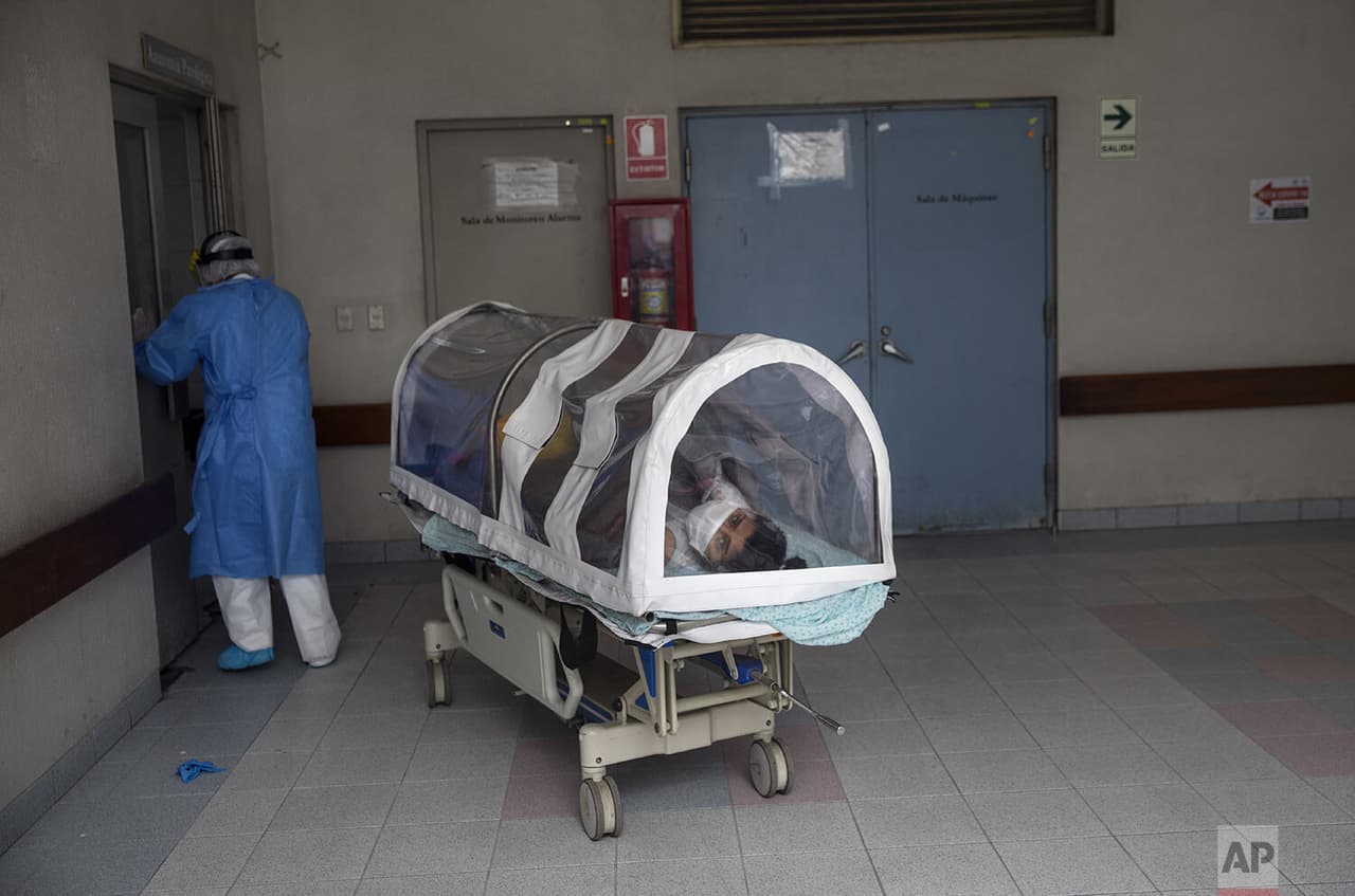 Una mujer embarazada con coronavirus 
<b>observa desde una cápsula de aislamiento,</b> mientras es trasladada a una sala especial para madres contagiadas en el centro médico.
<br>