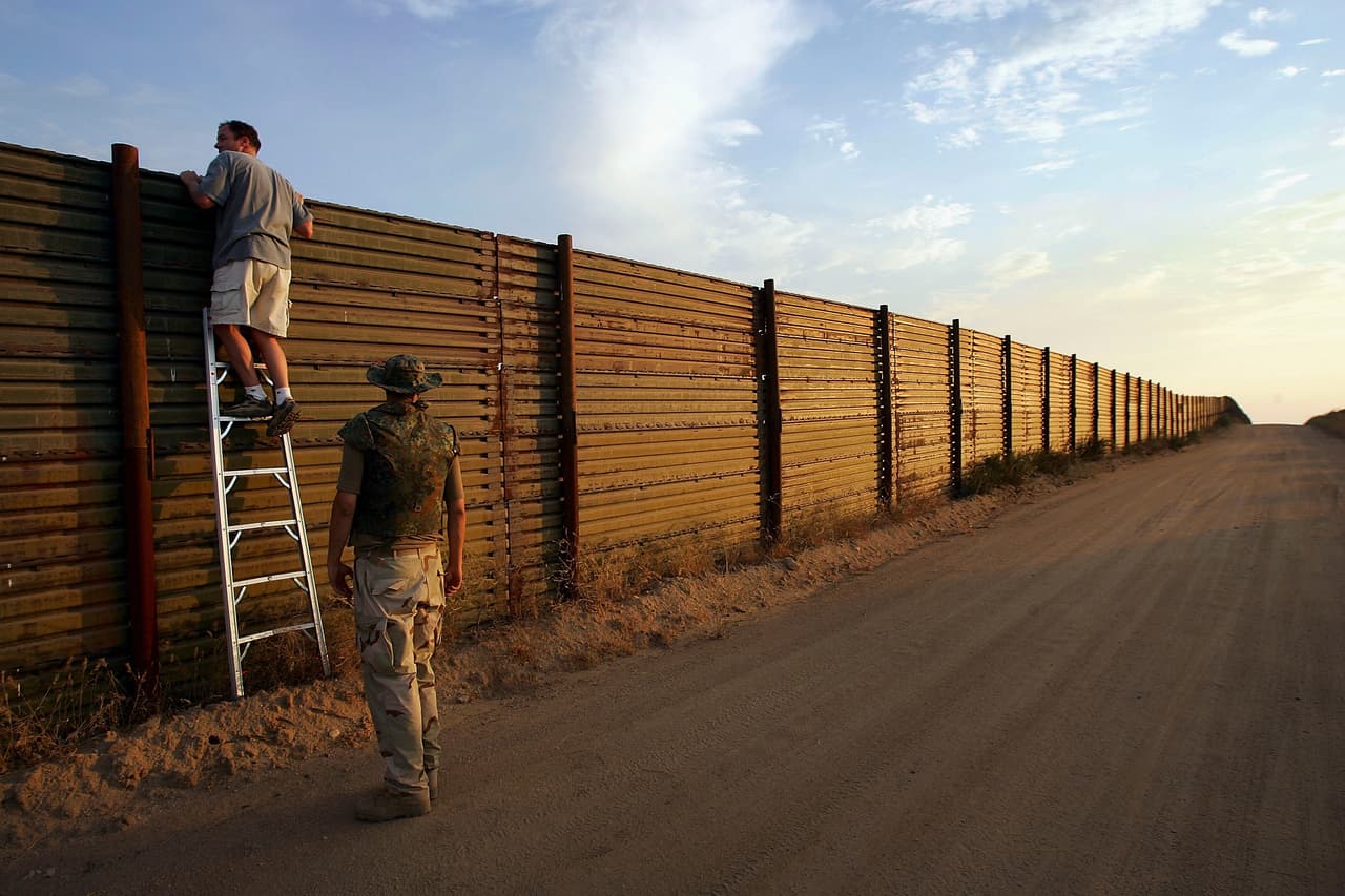 CAMPO, CA - JULY 19: Volunteers look over the US-Mexico border fence to see how illegal border crossers may jump the fence before going on the nightly patrol by citizen volunteers searching for people crossing into the US illegally from Mexico on July 19, 2005 near Campo, California in eastern San Diego County. The California Border Watch, members of the Arizona Minutemen, and other volunteers carry guns for self-defense and phone the US Border Patrol to report any illegal immigrants they find. They are shadowed by migrant activist protesters opposed to their actions who have been taunting them at regular intervals day and night. The new patrols come as the U.S. Congress considers immigration policy and how to treat the estimated 11 million illegal immigrants already in the United States. (Photo by David McNew/Getty Images)
