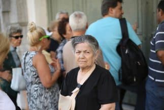 Un grupo de clientes aguarda en las afueras de un banco en Atenas para poder sacar su dinero retenido por el gobierno en medio de una grave crisis económica que afecta al país.