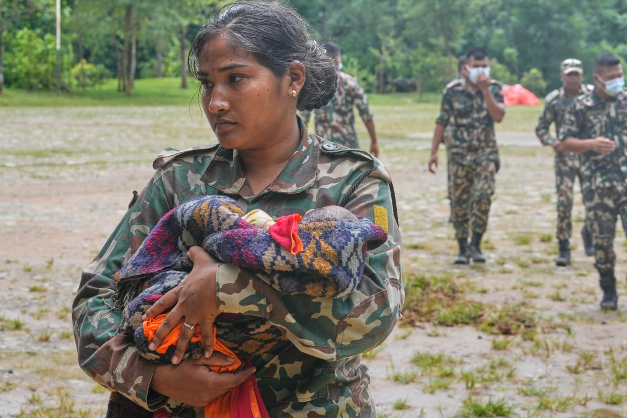 A Nepalese army soldier carries a newborn baby for the child's mother after they are rescued from an area cut off by flash flooding and for registration in Nepal's Nuwakot district, Saturday, Aug. 29, 2026. (AP Photo/Dar Yasin)