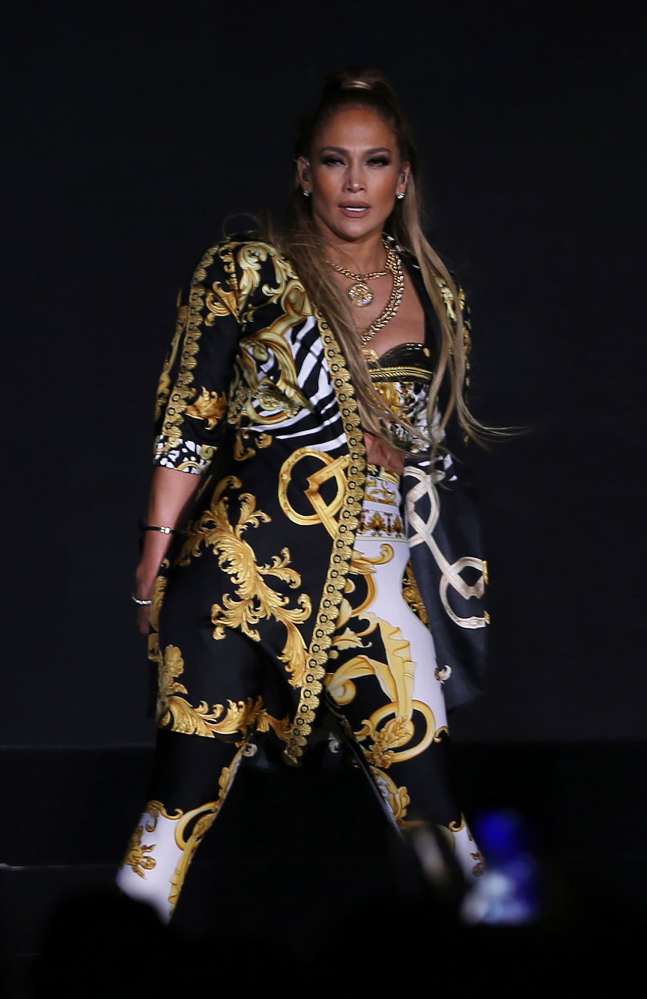 Con un conjunto de brasier, chaqueta y pantalón Versace, JLo movió las caderas con un modelo de la última colección de la exclusiva línea de alta costura.