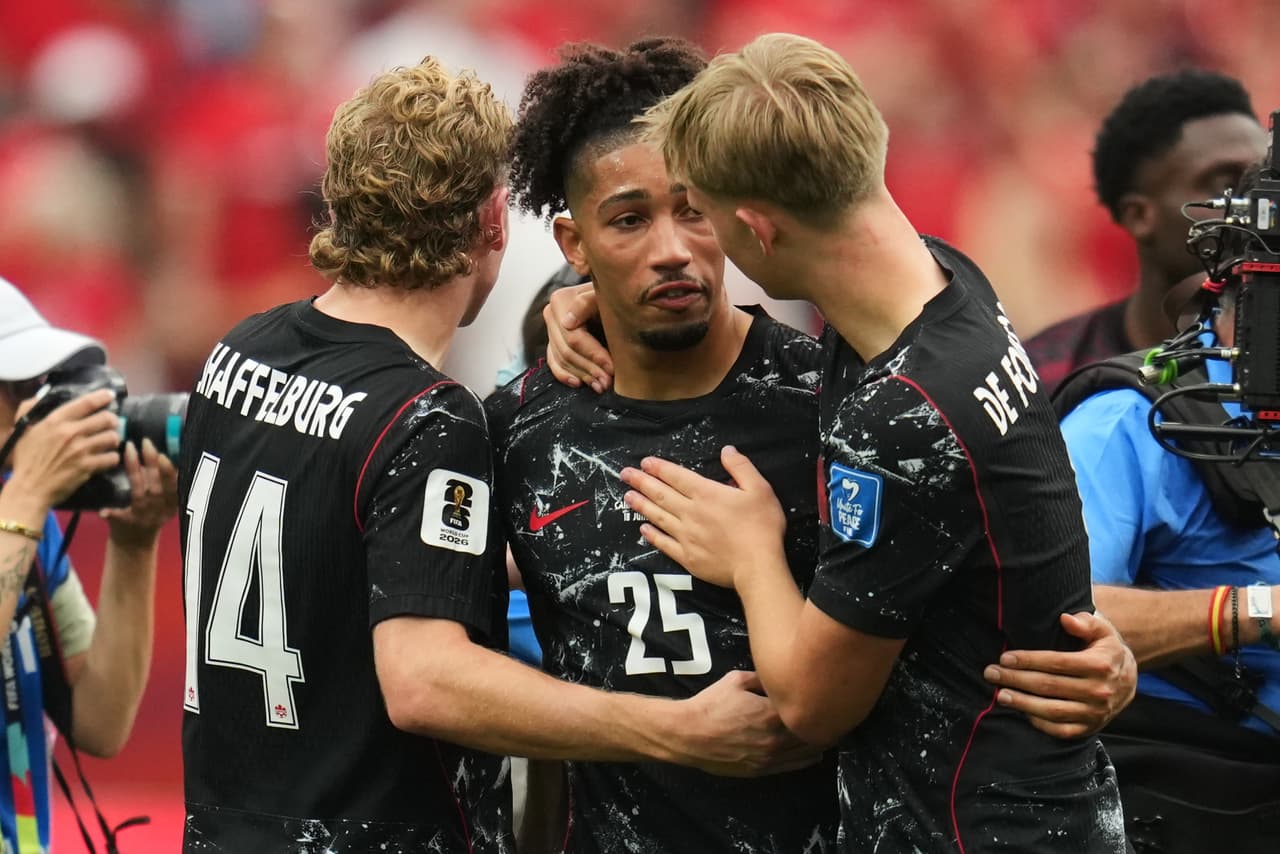 Nathan Saliba, de Canadá (en el centro), se emociona y es consolado por Jacob Shaffelburg (a la izquierda) y Luc de Fougerolles (a la derecha) tras la victoria de su equipo en el partido de futbol del Grupo B de la Copa Mundial contra Qatar en Vancouver, Columbia Británica, el jueves 18 de junio de 2026.