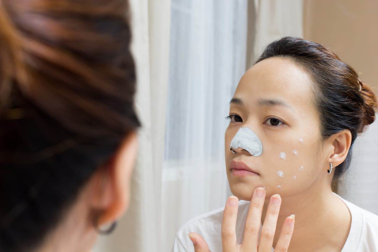 Mujer asiática untando crema en su rostro