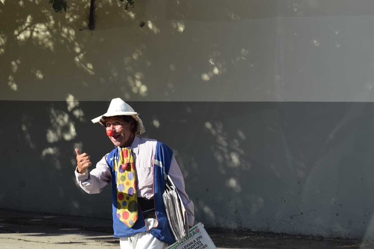 Un hombre disfrazado de payaso vende periódicos de Tijuana.