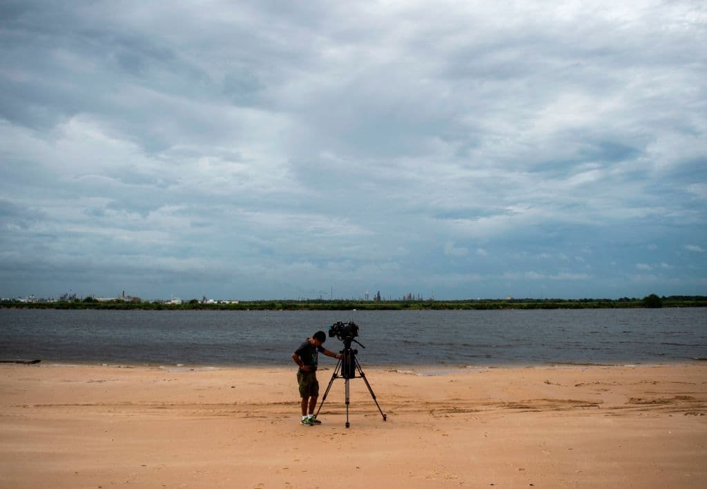 Un camarógrafo de televisión se protege contra el viento del huracán Laura en una playa en Lake Charles, Louisiana.