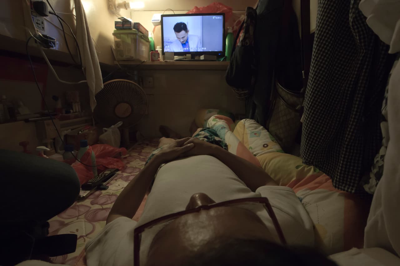 Simon Wong, un desempleado, mira la televisión de su ‘casa’ en Hong Kong.