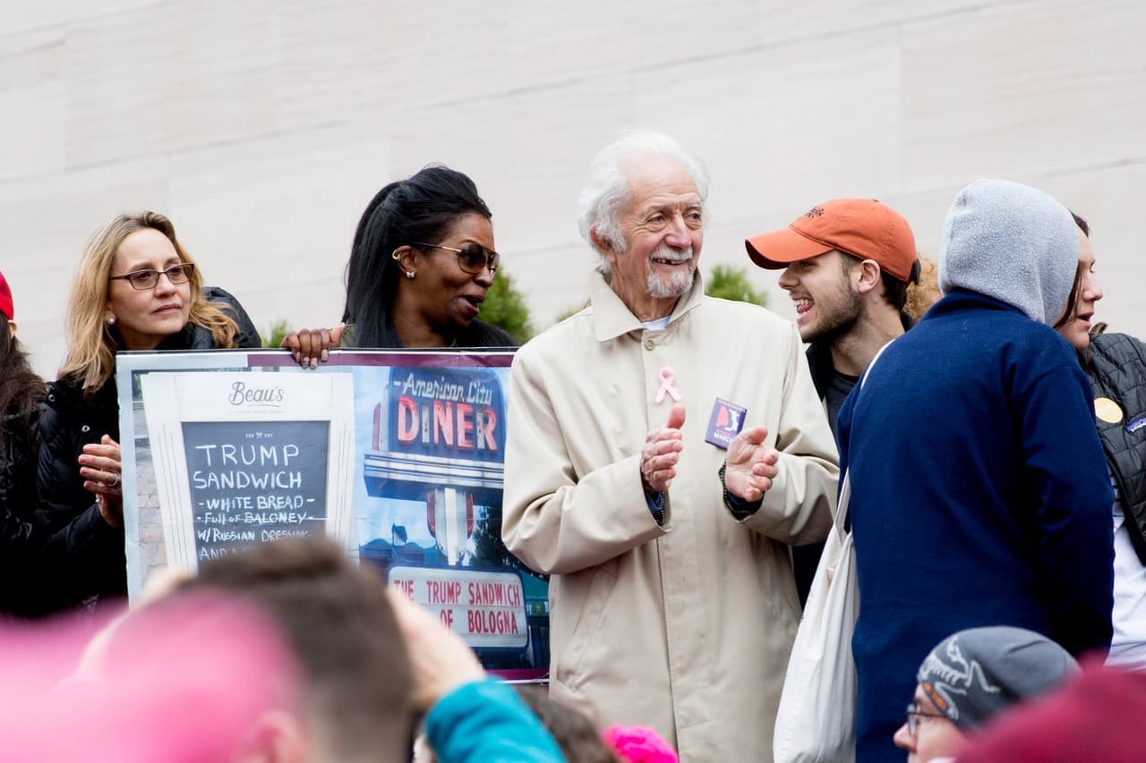 A este señor se le vio bailando y aplaudiendo durante la manifestación. Al lado , una pancarta muestra "el sándwich Trump": pan blanco con aderezo ruso, dice.
