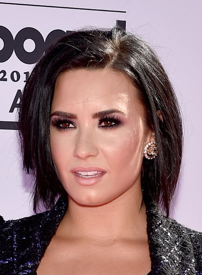 Demi Lovato también decidió llevar un maquillaje en el que con ayuda de las sombras, el delineador, pestañas postizas y máscara de pestañas hizo destacar su mirada. Los smoky eyes tienen un toque de sombra morada. El tono nude que llevo en sus labios ligeramente rosados le queda perfecto a su tono de piel.