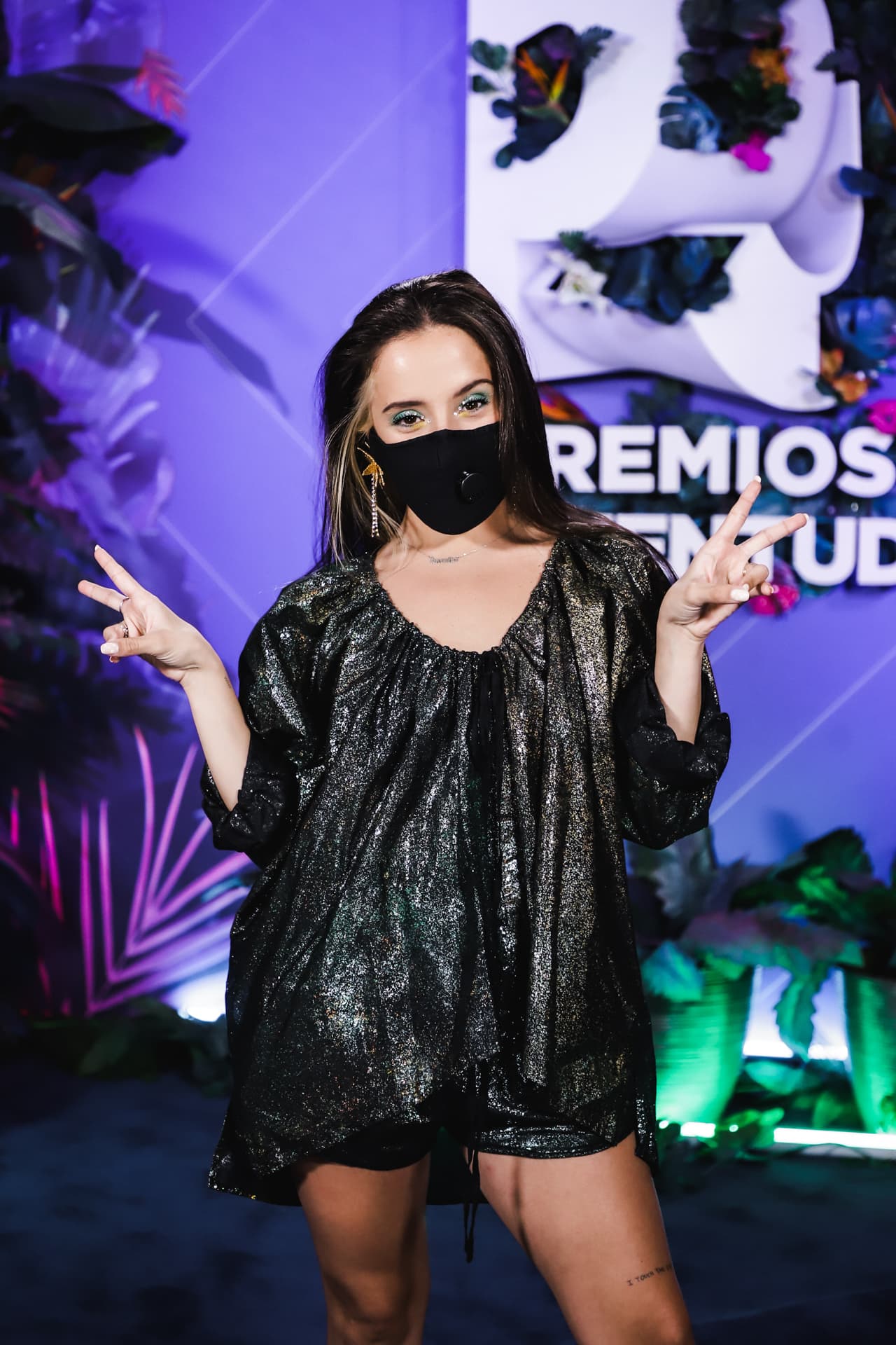 La actriz y cantante venezolana asistió al evento vistiendo un short y un blusón negro con brillos tornasolados.