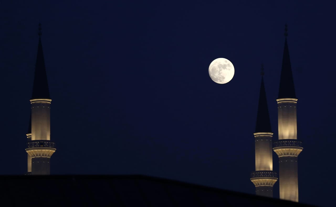 La luna se observa entre los miranetes de una mezquita en Ankara (Turquía).
