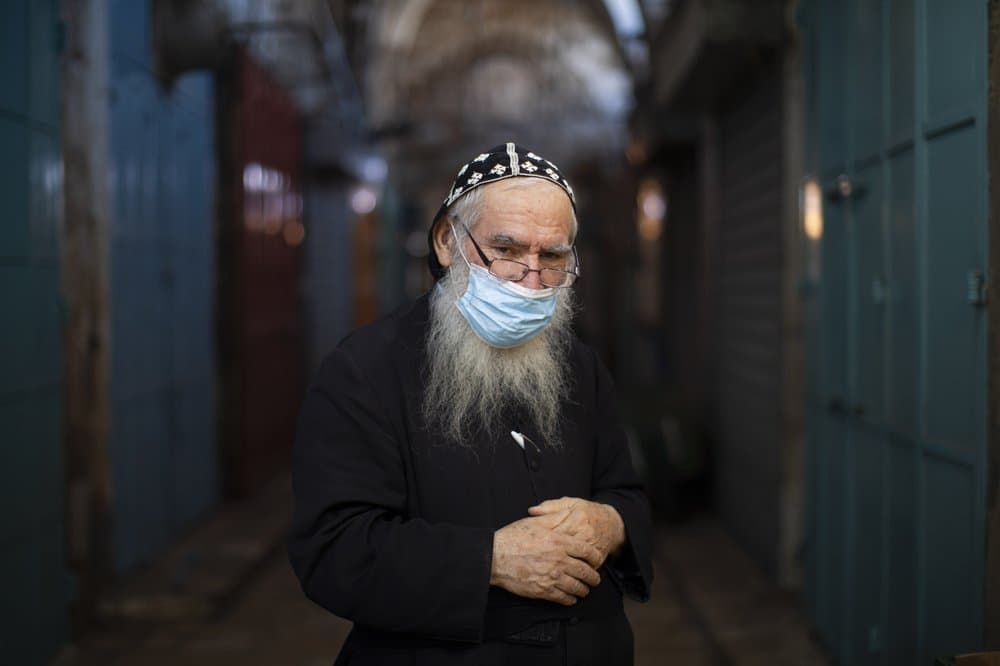 El sacerdote ortodoxo sirio, Shimon Jan, de 70 años, posa para un retrato con su máscara protectora en los callejones de la Ciudad Vieja de Jerusalén, el 21 de julio de 2020. 
<b>Jan dice "Estoy aconsejando a todos que usen máscaras no solo por la ley, también porque la vida es lo más importante".</b>