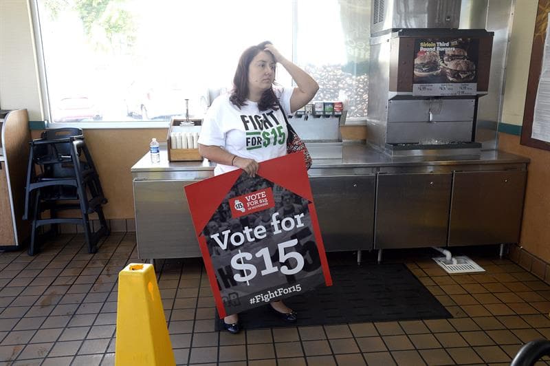 Una manifestante sostiene un cartel durante una protesta para pedir el aumento en el salario mínimo de 15 dólares la hora en un restaurante McDonald's en el centro de Los Ángeles. (Foto: EFE).