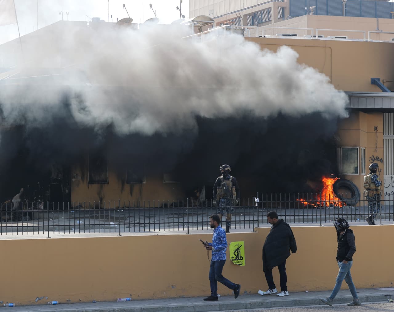 Miembros de las fuerzas de seguridad iraquíes montan guardia en la entrada principal del edificio de la embajada estadounidense en Bagdad, durante las protestas por el bombardeos a las bases de la milicia Hashd al-Shaabi, de signo proiraní.