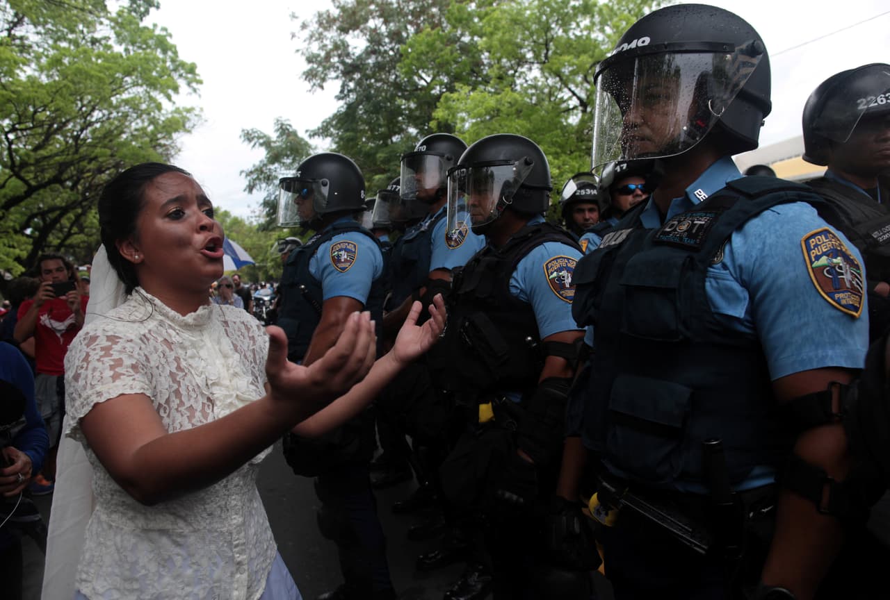 Una mujer vestida de novia le habla a los policías que resguardaron las marchas. (Reuters)