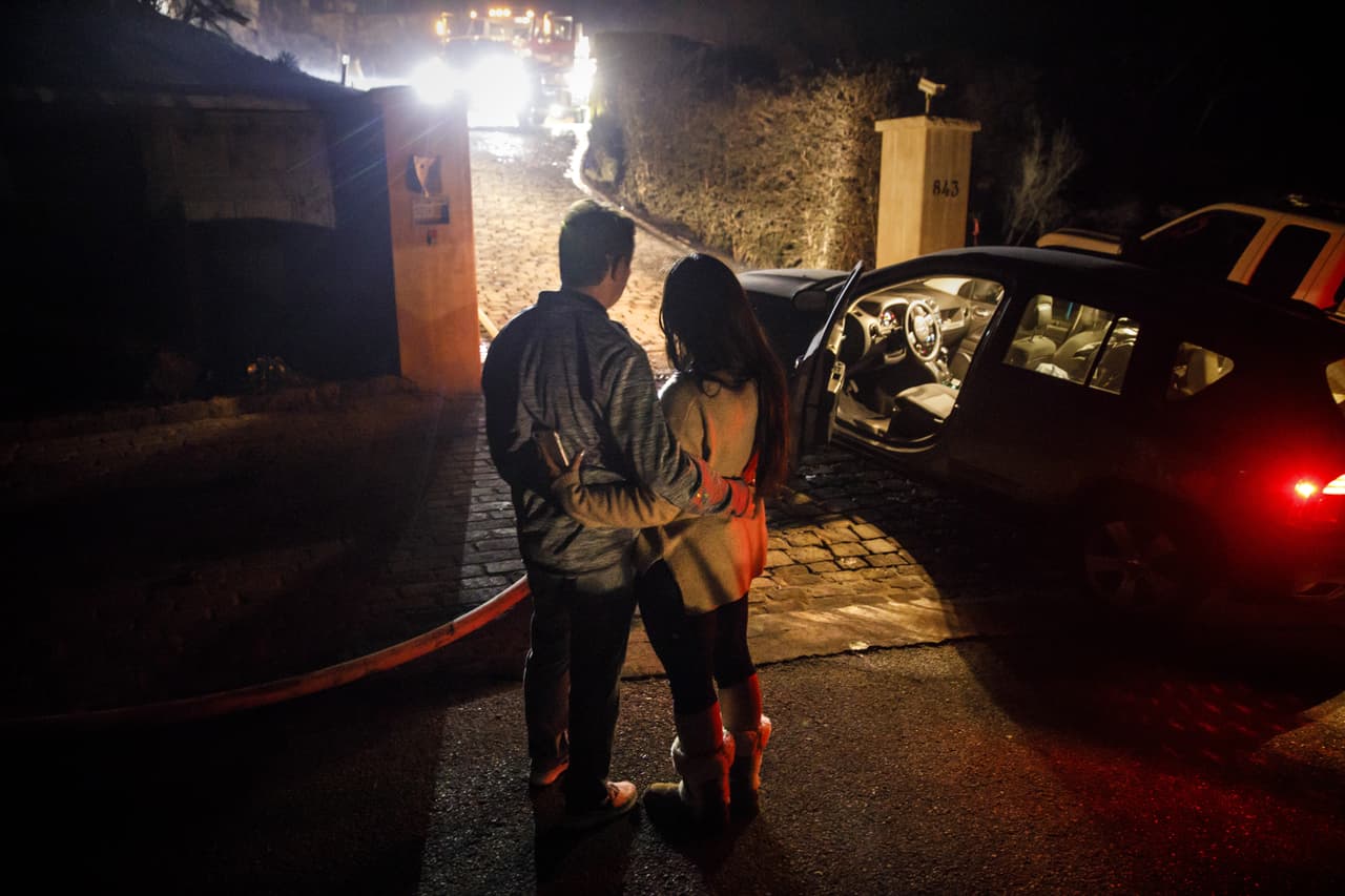 Michael Behrman y su esposa Sonia González miran a los bomberos trabajar sobre los restos de su casa.