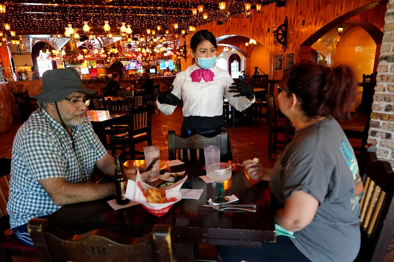 Comensales en un restaurante de Houston, Texas, atendidos por una mesera protegida con una mascarilla el 1 de mayo. Este local reabrió su comedor con capacidad limitada, luego de que la orden de 'quedarse en casa' expirara el 30 de abril en este estado. 
<u><a href="https://www.univision.com/noticias/salud/mapa-actualizado-del-coronavirus-cifras-de-casos-confirmados-y-fallecidos">Vea aquí nuestro mapa actualizado del coronavirus: cifras de casos confirmados y fallecidos </a></u>
