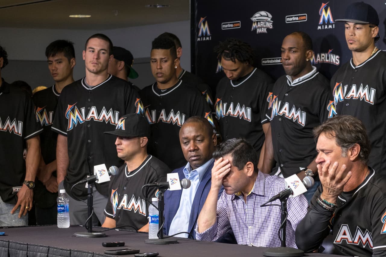 David P. Samson, centro, presidente de los Marlins de Miami, se cubre el rostro durante una conferencia de prensa en que se anunció la muerte del lanzador cubano José Fernández, el domingo 25 de septiembre de 2016, en Miami. Fernández, que escapó de Cuba para convertirse en una de las máximas estrellas del béisbol de Grandes Ligas, murió en un accidente en bote a primeras horas del domingo. Tenía 24 años. (AP Foto/Gaston De Cardenas)