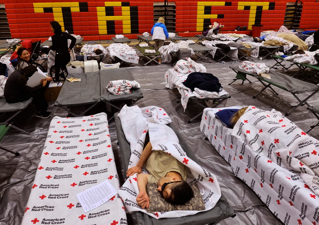 Los evacuados de un incendio descontrolado descansan en catres y mantas suministrados por la Cruz Roja en el gimnasio de Taft Charter High School en la sección de Woodland Hills en Los Ángeles. AP Photo/Richard Vogel