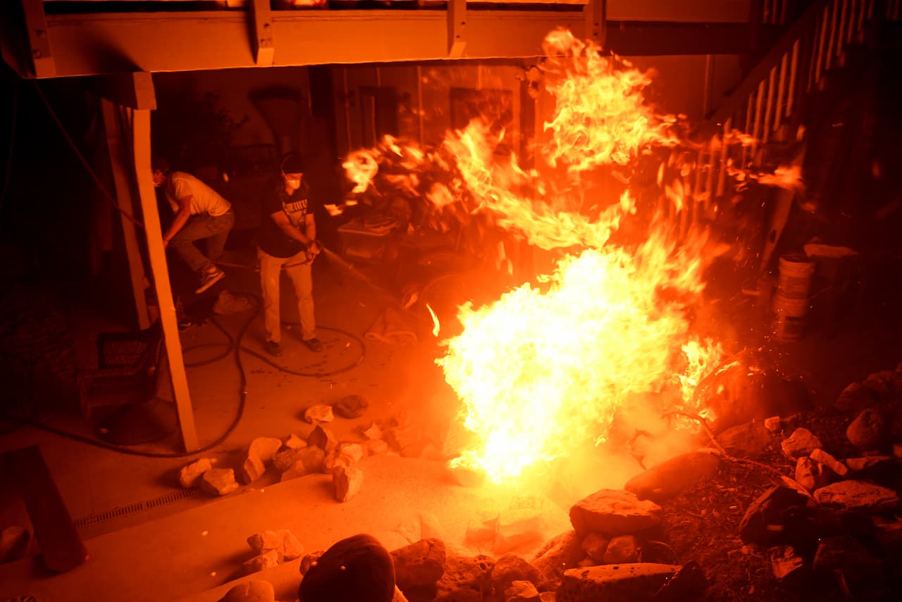 Residentes de La Conchita intentan luchar con el fuego en una de las viviendas incendiadas en el condado de Ventura.