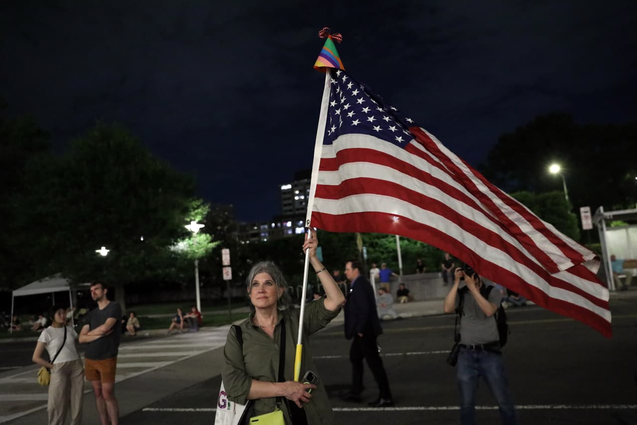 Varias personas esperan a que se retire el nombre del presidente Donald Trump del Centro John F. Kennedy.
