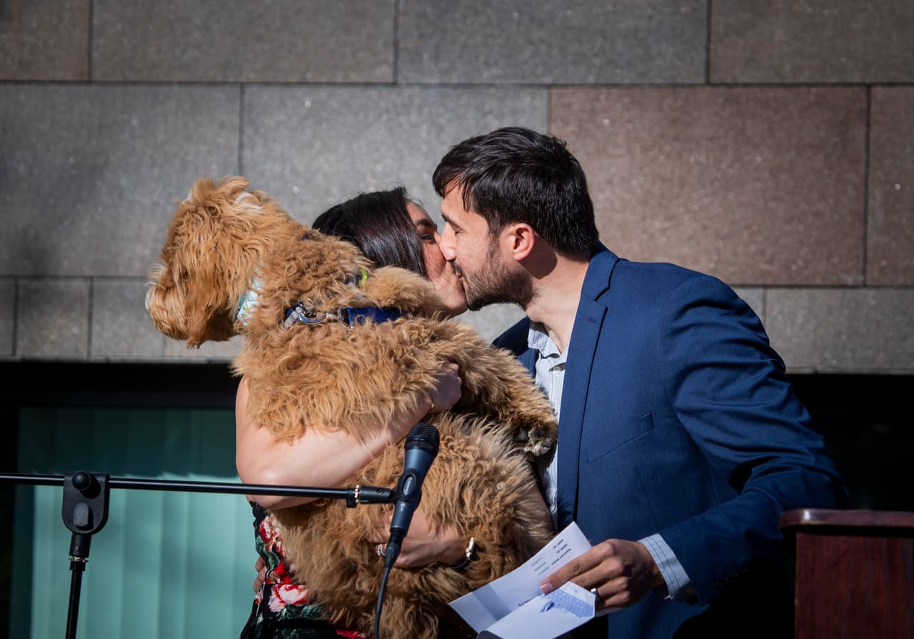 Alyssa Lo-Mina, estudiante de medicina de la UCI , sostiene a su perro Podrick y besa a su esposo Tommy Mina emocionada porque continuará su entrenamiento médico de posgrado en obstetricia y ginecología en la Universidad del Sur de California.