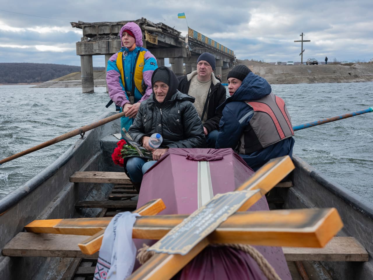 A woman sits in a boat crossing the Siverskyi-Donets river near Staryi-Saltiv, Kharkiv region on Wednesday Jan. 4, 2023, transporting the coffin containing her dead son, a soldier who was killed in fighting with Russians. (AP Photo/Erik Marmor)