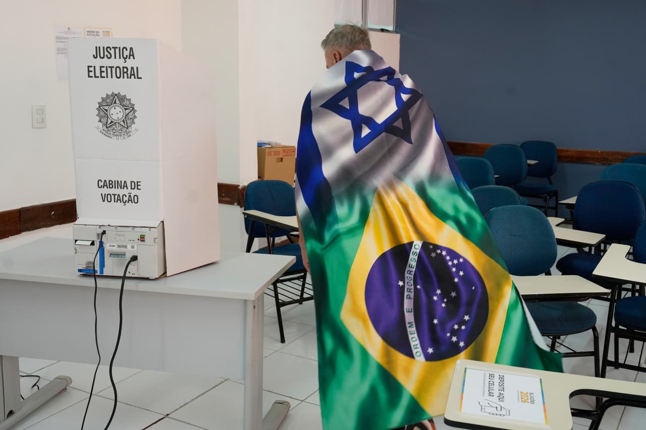Un votante envuelto en una bandera que combina los diseños de las banderas israelí y brasileña se acerca a una máquina de votación electrónica durante la segunda vuelta de las elecciones presidenciales en Brasilia, Brasil, el domingo 25 de octubre de 2026.