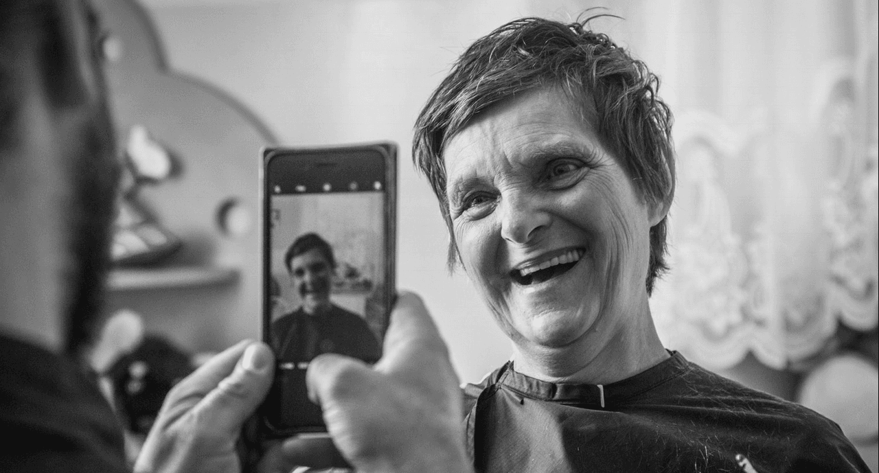 Sascha Breuer fotografía con su celular a una mujer luego de hacerle un corte de cabello.