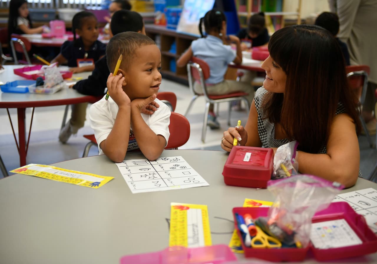 In this Friday, Sept. 29, 2017 photo, Elionet Saez Martin, of Puerto Rico, left, works with his kindergarten teacher Rachael Leupold, right, at Chamberlain Elementary School in New Britain, Conn. As Hurricane Maria churned toward Puerto Rico, Elionet's mother put him and his 9-year-old brother, Eliot, on a plane to be with their grandfather in Connecticut. The brothers are among the first of what is expected to be large numbers of Puerto Rican children enrolling in school districts on the U.S. mainland, particularly in urban areas from Florida to Massachusetts with large Puerto Rican populations. (AP Photo/Jessica Hill)