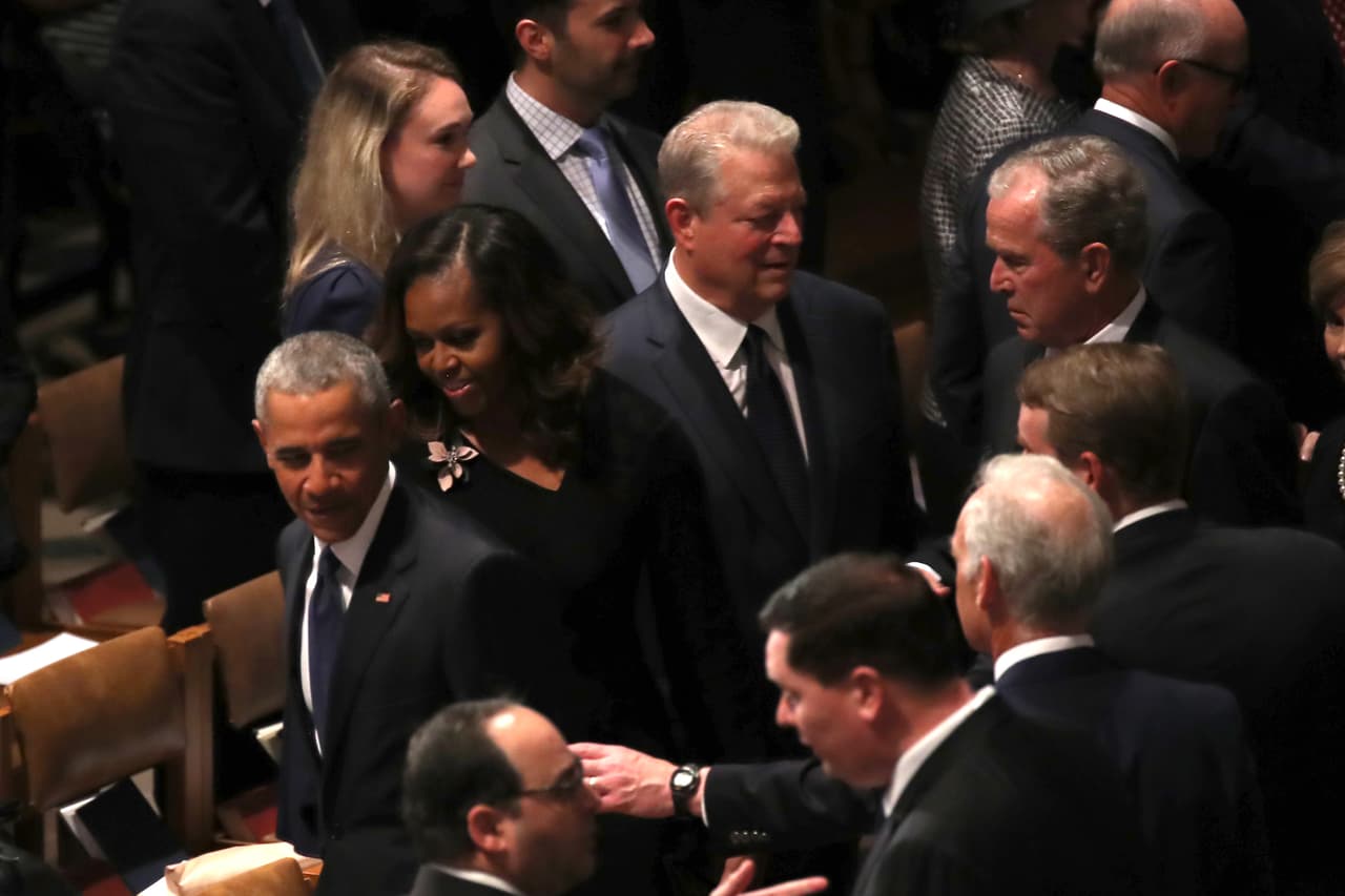 Barack y Michelle Obama, Al Gore y George W. Bush buscan sus asiento en la la Catedral Nacional en Washington.
