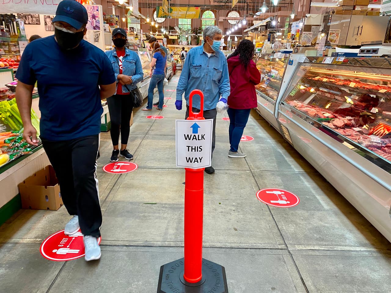 Los clientes de un automercado de Washington DC atienden las nuevas señales colocadas en el suelo, una medidas que este tipo de establecimientos ha tomado para mantener separadas a las personas. 17 de mayo.