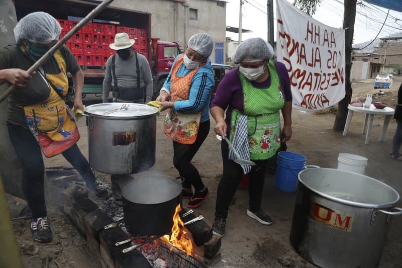 Mujeres preparan comida para un grupo de familias que enfrentan dificultades por la pandemia del nuevo coronavirus en Villa María del Triunfo en Lima, Perú.