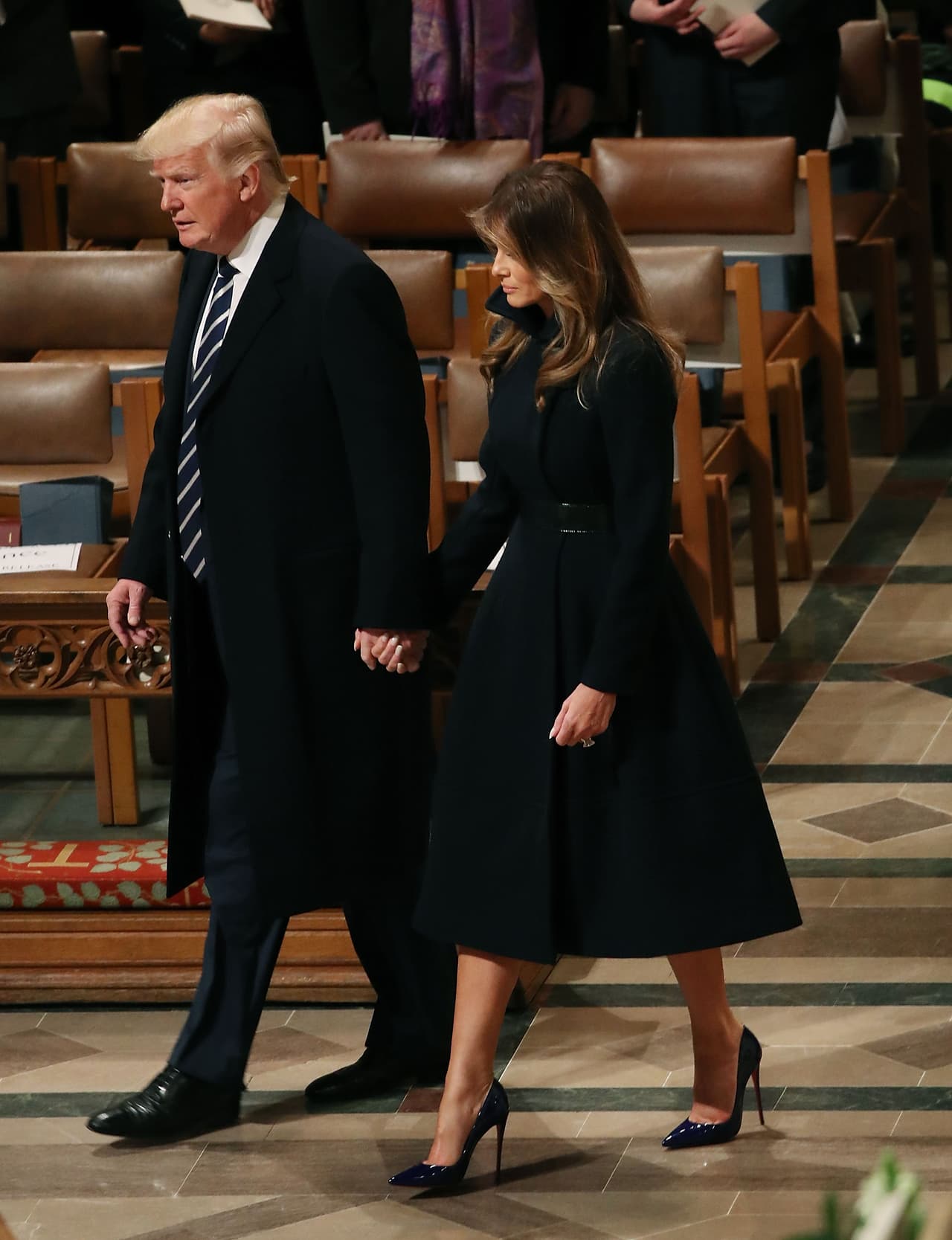 Un día después de la posesión presidencial, Melania Trump asistió de la mano de su esposo al National Prayer Service en donde quiso lucir austera y respetuosa
<b> con un abrigo tipo vestido de lana negra y cinturón, acompañado de unos altísimos tacones violeta de Louboutin.</b>