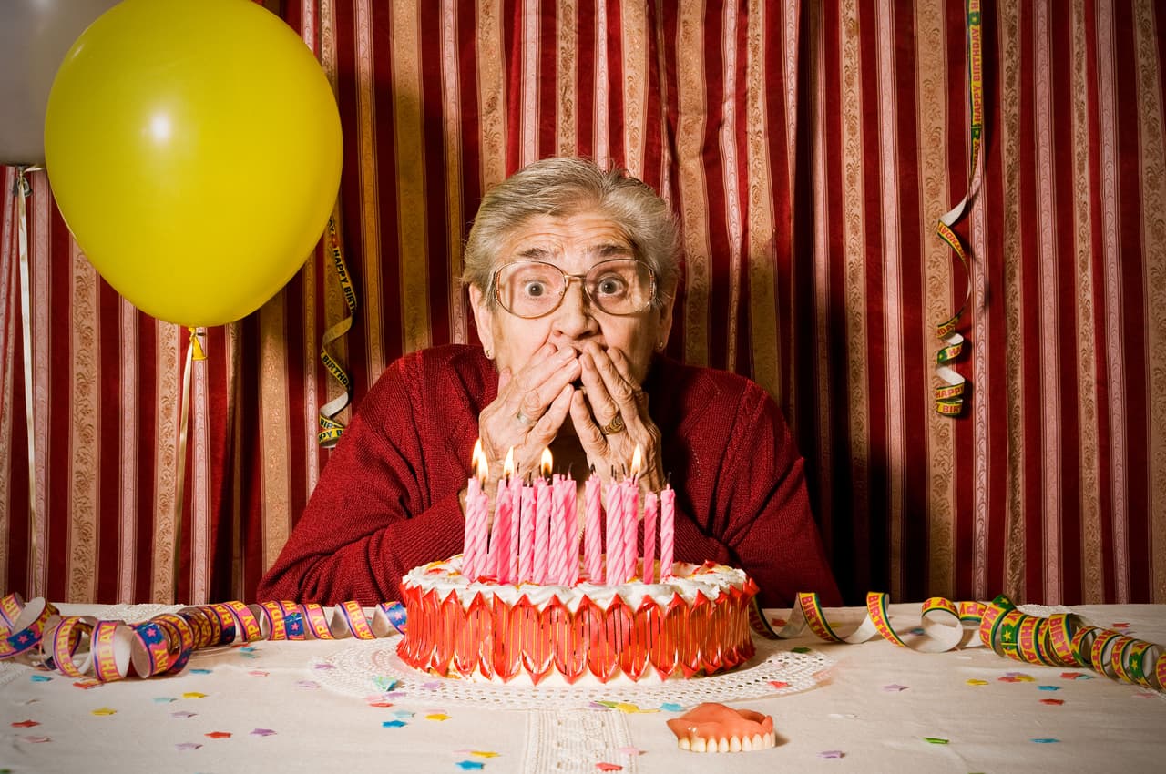 Abuelita cubriendo su boca en festejo de cumpleaños.