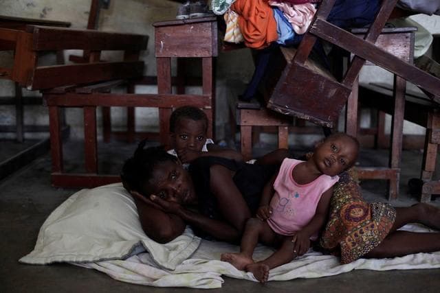 A woman with two of her children rest on the floor at the shelter set up in a school ahead of Hurricane Matthew in Les Cayes, Haiti, October 3, 2016.