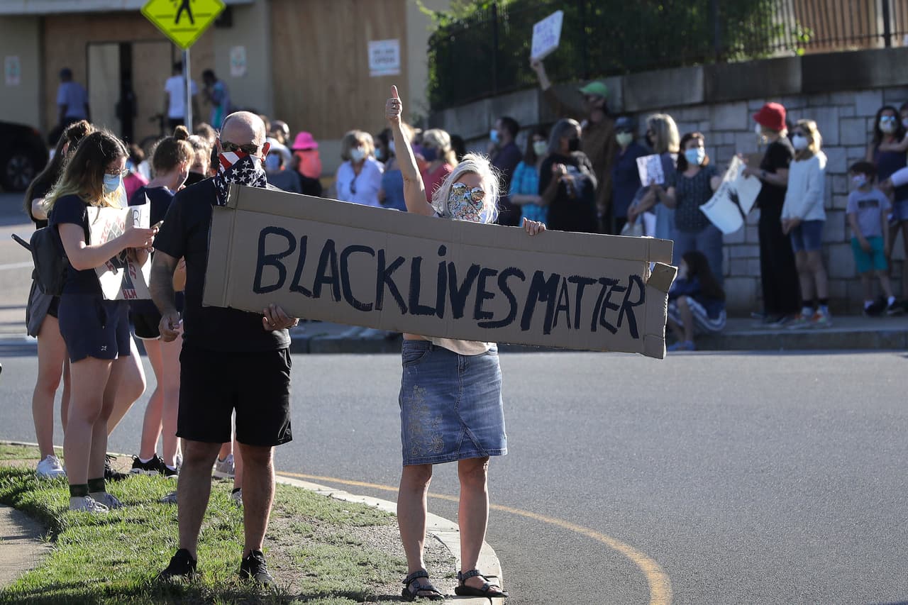 Manifestantes mostraron carteles durante una protesta contra la brutalidad policial, este lunes en el barrio de West Roxbury de Boston, recordando el caso de George Floyd, muerto después de que un oficial de policía de Minneapolis presionara su rodilla contra el cuello del afroestadounidense, que ya estaba en el suelo inmovilizado por otros tres agentes.