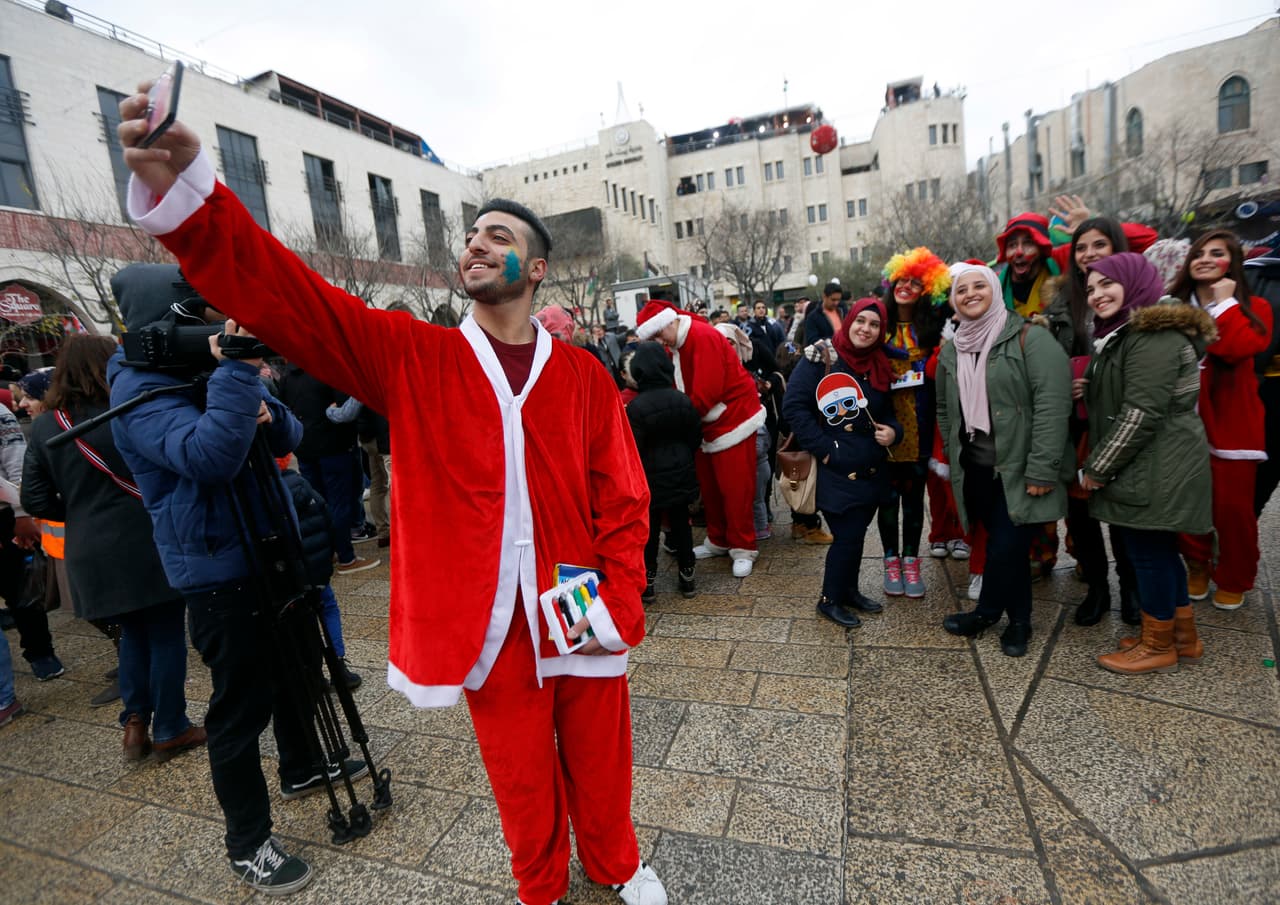 Un palestino vestido de Santa Claus toma una foto en la Nochebuena en la Plaza del Pesebre, fuera de la Iglesia de la Natividad.