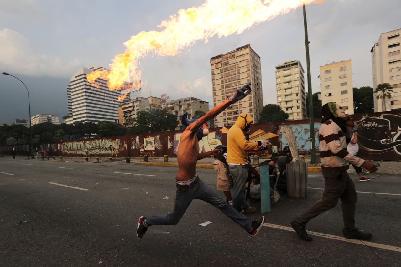 An opposition protester launches a 'Molotov cocktail' at police. April 19, 2017.
