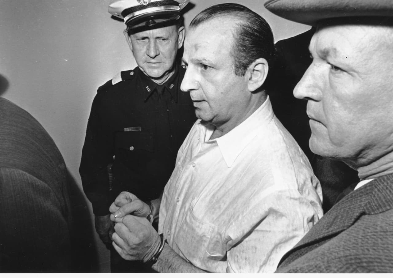 La muerte de Lee Harvey Oswald levantó un sinnúmero de suspicacias en la opinión pública estadounidense. Jack Ruby declaró que no había planeado el asesinato, que fue una reacción momentánea en contra del magnicida. Murió en 1967 de cáncer de pulmón. En la fotografía mientras era trasladado por la policía de Dallas, después de dispararle a Oswald.