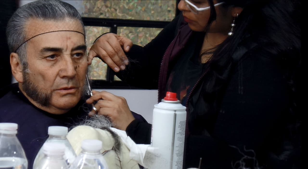 La caracterizadora pega con mucho cuidado los vellos de la barba.