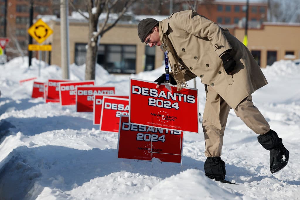 Un simpatizante de Ron DeSantis coloca carteles de su campaña en la nieve en Cedar Rapids.