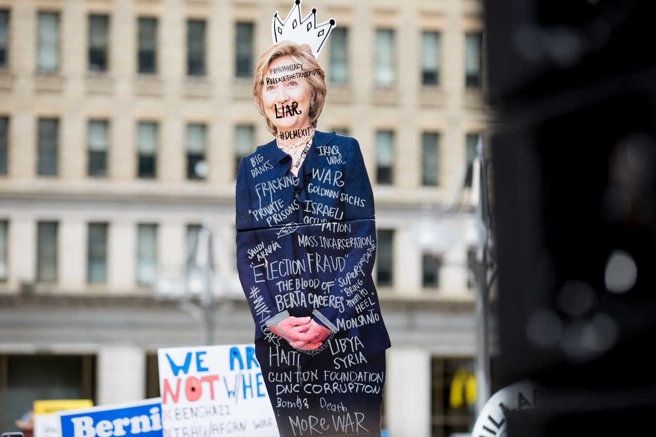 MARTES 26 DE JULIO. 2:33 PM. El grupo de manifestantes reunidos en el centro de Filadelfia, aún apoyan a Bernie Sanders pero no están de acuerdo en seguir a Hillary Clinton y al partido demócrata en la carrera presidencial. Sobre una fotografía de la candidata se ven escritos los temas que consideran responsabilidad de Clinton: la ocupación israelí, la guerra de Iraq, el fracking, la muerte de Berta Cáceres, prisiones privadas, Libia, Siria, entre otras.