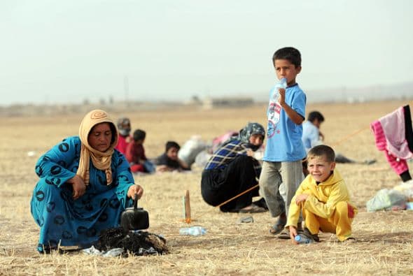 Niños refugiados kurdos sirios rodean a su madre mientras ella hace té. Este es uno de los campamentos de refugiados al sudeste de la provincia de Sanliurfa, en Suruc, Turquía.
