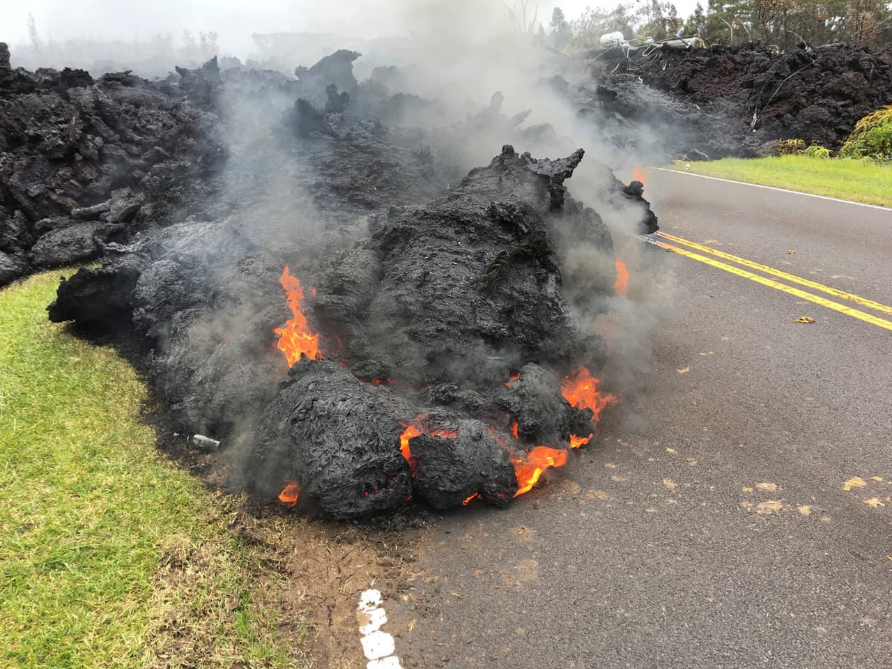 La lava del volcán Kilauea sobre una carretera en Leilani Estates. Si bien algunas grietas siguen emitiendo chorros de lava, otras se han detenido.