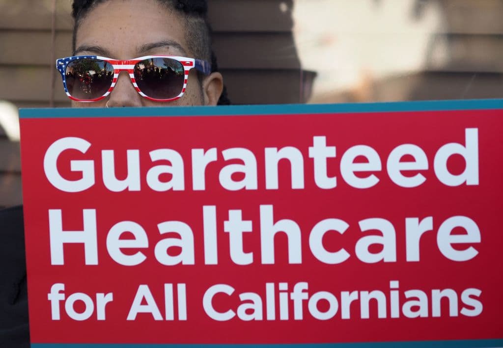 People rally in favor of single-payer healthcare for all Californians as the US Senate prepares to vote on the Senate GOP health care bill, outside the office of California Assembly Speaker Anthony Rendon, June 27, 2017 in South Gate, California. Rendon announced last week that Senate Bill SB 562 - the high-profile effort to establish a single-payer healthcare system in California - would be shelved, saying it was "incomplete." / AFP PHOTO / Robyn Beck (Photo credit should read ROBYN BECK/AFP/Getty Images)