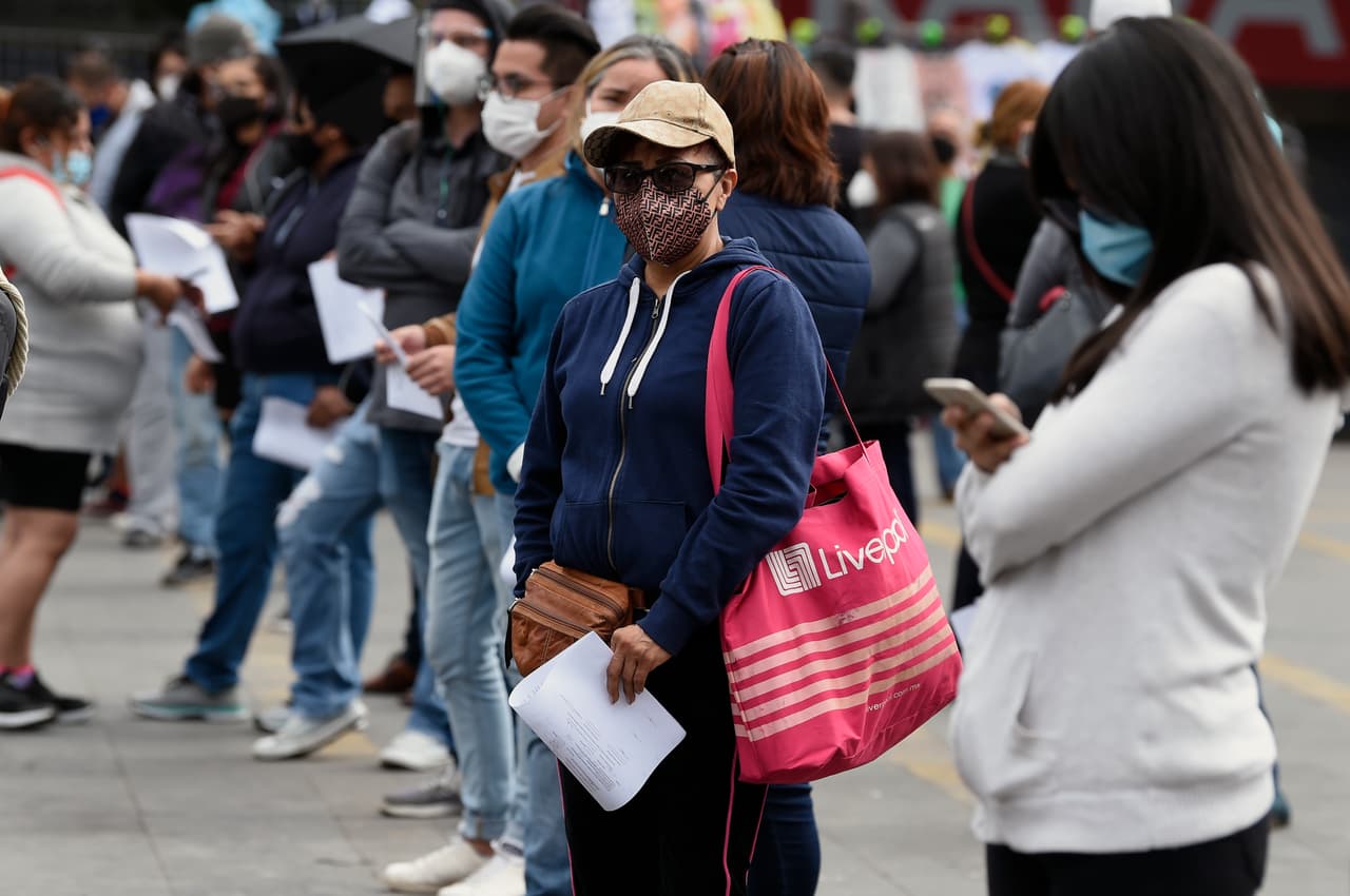 Habitantes de la Ciudad de México con máscaras protectoras esperan en fila para hacerse una prueba rápida covid-19.