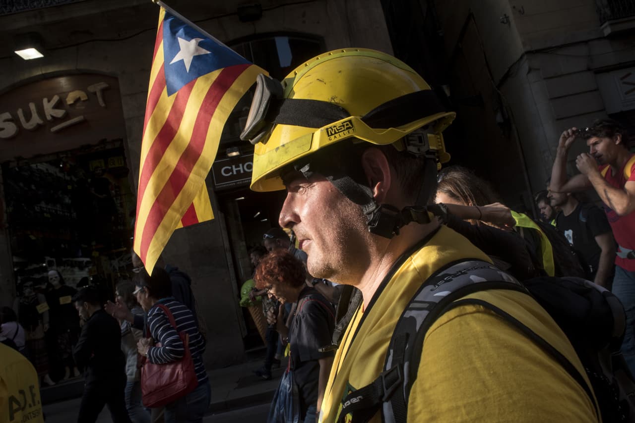 La jornada dejó imágenes de festejo, pero también de tensión y tristeza por la ruptura que supone la decisión de una parte de los parlamentarios catalanes. En la fotografía, un bombero catalán celebra la votación que aprobó la declaración de independencia en una calle de Barcelona.
<br>