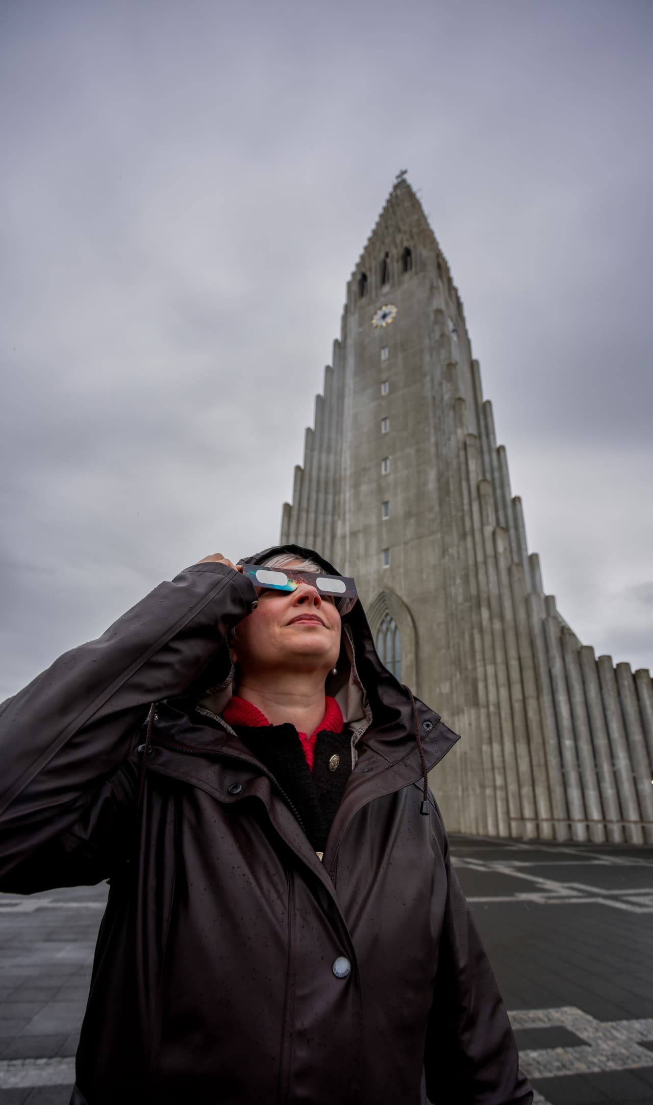 Anita Sauckel, empleada de la Universidad de Islandia, utiliza gafas para eclipses solares para mirar hacia el sol frente a la iglesia Hallgrímskirkja, antes de un eclipse solar en Reikiavik, Islandia, el miércoles 12 de agosto de 2026.