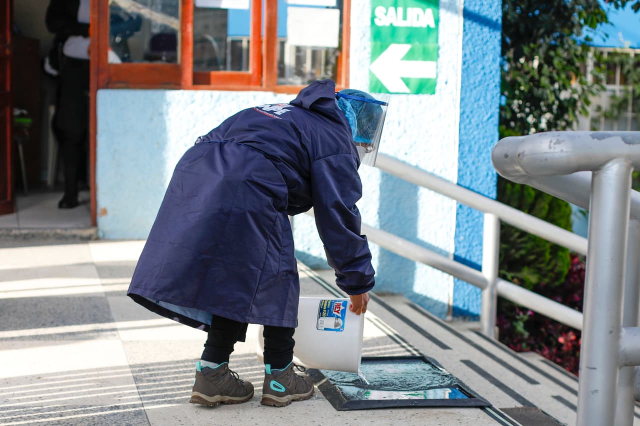 Además de chequear la temperatura en los centros de votación, los electores deben desinfectarse los zapatos al entrar en las urnas. En la imagen, una representante de la ONPE cumple con los protocolos sanitarios en Huaraz, Perú.