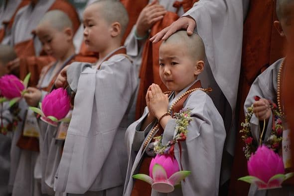 Varios jóvenes se reunieron ataviados de una túnica gris, con unas flores rosas de plástico sostenidas sobre sus manos y sus collares religiosos colgados del cuello.